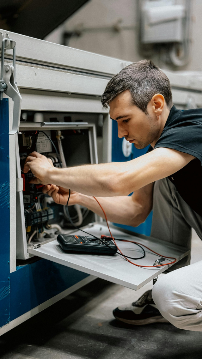 A technician servicing equipment inside an industrial control panel