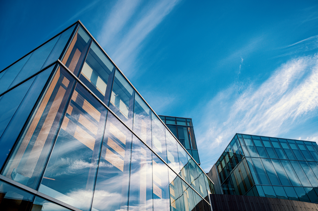 Modern glass office buildings layered against a blue sky
